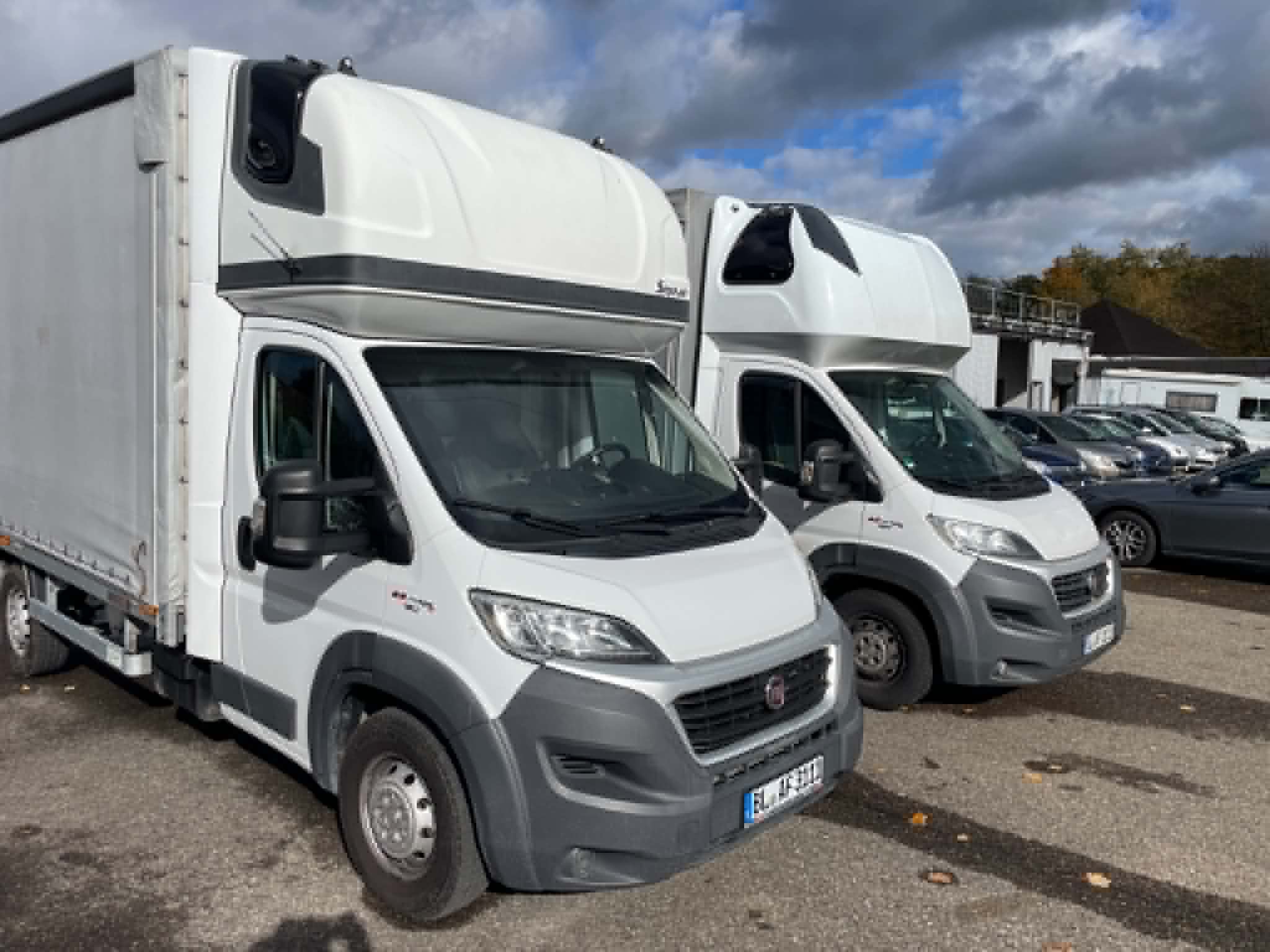 Weiße Transporter mit Schiebeplanenaufbau auf einem Parkplatz